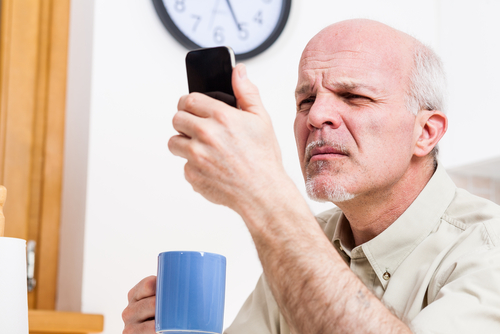 Man Struggling to Read Phone Screen due to Cataracts